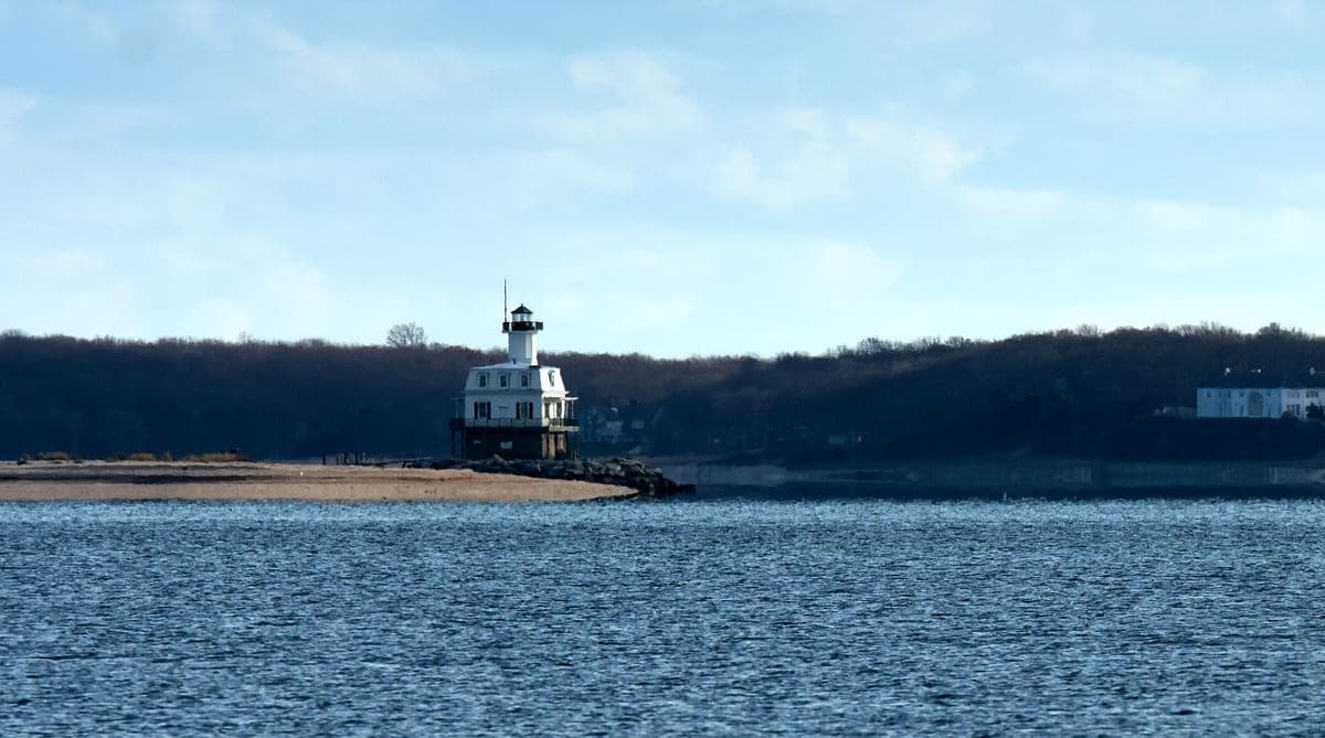 Long Beach Bar lighthouse, Peconic Bay, NY — the white screwpile cottage and its lantern on a riprap base at the end of the Long Beach Point spit.